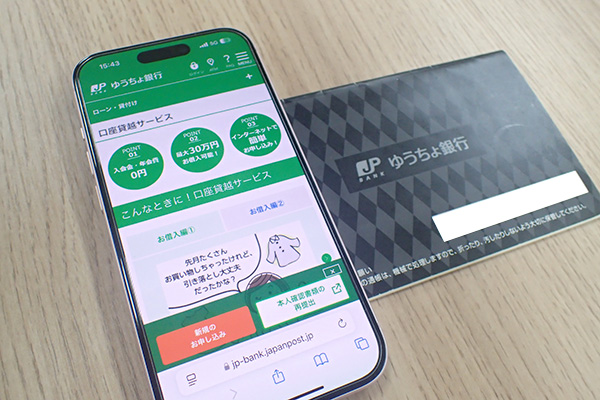 ゆうちょ銀行の通帳と公式HPを表示させたスマホ