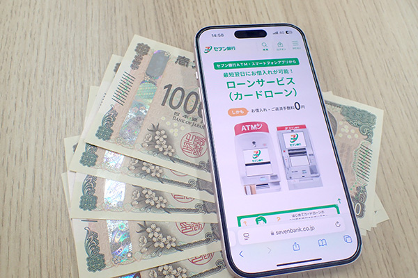 セブン銀行カードローンの公式HPを表示させたスマホとお金